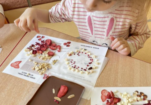 dzieci przekładają owocowy wzór na płynną czekoladę w formach